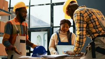 African american people talking about merchandise and retail store distribution, packing cardboard boxes with tools in warehouse. Cheerful storage room employees working on industry production. photo