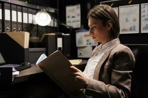 caucásico inspector leyendo criminología informe, trabajando tiempo extraordinario a delincuente caso en archivar habitación. privado detective analizando crimen escena evidencia, buscando para nuevo pistas a captura sospechar foto