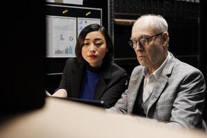 Bookkeeping employees working in administrative file cabinet office surrounded by statistical chart graphics. Consultancy bureaucratic workplace filled with business folders photo