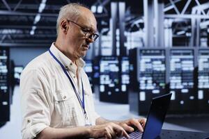 Licensed expert using laptop, setting up high bandwidth dedicated multiplayer gaming servers in supercomputer room to accommodate more traffic from worldwide locations and avoid obstructive lag photo