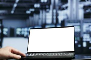 Close up shot of mock up laptop used by proficient repairman in data center using server cabinets to deliver massive computing power, control network resources, process and store datasets photo