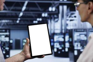 Computer scientists using mock up tablet to check blade servers, close up. Machines in computer network security data storage business providing processing and memory resources for several workloads photo