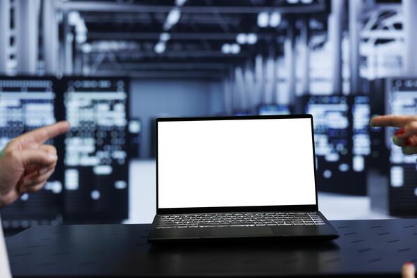 Close up shot of mock up laptop used by computer scientist in data center using server racks to deliver massive computing power, control network resources, process and store datasets