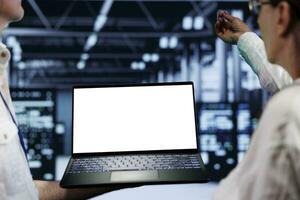 Close up shot of mock up laptop used by professional mechanic in data center server room delivering massive computing power, capable of processing and storing vast amounts of datasets photo