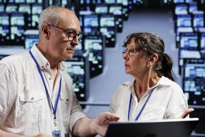 Senescent computer operators working to maintain uptime in high tech location. Skillful experts brainstorming solutions to data center server rigs crashing, trying to fix components photo