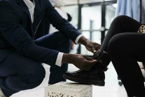 Retail employee helping african american client with purchase in shopping center. Stylish customer trying stylish shoes, buying trendy merchandise in boutique, commercial activity. Close up photo