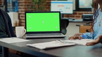 People having laptop with greenscreen on desk, talking about development in briefing meeting. Corporate workers looking at blank mockup chroma key isolated display, startup office. photo