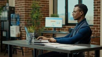 Young employee using laptop at desk, reading official reports information to help increase profit. Company analyst reviewing data statistics to build new business vision for development. photo