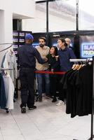 Eager emotional shoppers lined up outside of department store quarreling with clothing store security guard patrolling entrance, angry people tired of waiting for Black Friday deals in long line photo