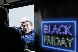 Security officer opening shopping mall entrance door on Black Friday. Crazy fanzy crowd of excited diverse people shoppers breaking into store to get best deals during seasonal sales photo