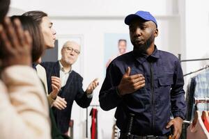 Shoppers yell at African American man security officer, waiting in line at fashion store entrance. Diverse people customers being rude and unpleasant with shopping mall employee during Black Friday photo