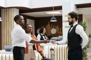 Bellboy accepting cash from hotel guest in reception lobby, offering luxury services to carry luggage at front desk. Young man giving tip to hotel concierge, helping with suitcases. photo