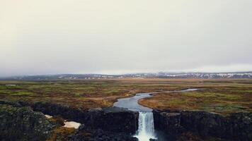 Majestic oxarafoss cascade panorama, aerial view of icelandic waterfall running down of mountain. Massive river stream flowing and falling off big rocky cliffs in iceland. Slow motion. photo