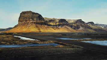 Drone shot of majestic mountain in iceland, spectacular roadside and snowy fields. Icelandic massive hills and brown frozen lands in scandinavian landscapes. Slow motion. photo