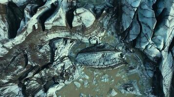 Drone shot of ice caves in iceland, massive icy rocks and dark crevasses on vatnajokull glacier cap. Diamond shaped ice mountains forming icelandic scenery with frozen water. Slow motion. photo