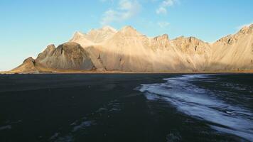 Aerial view of vestrahorn mountains in iceland, stokksnes beach and peninsula forming beautiful nordic landscape. Spectacular landscape with black sand beach, icelandic nature. Slow motion. photo