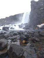 Gullfoss waterfall in nordic landscape, majestic icelandic scenery with snowy hills and icy water falling off cliff. River stream on top of frosty rock mountains, scandinavian cascade near valley. photo