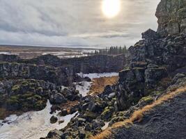 Steep river valley with huge rocks in Thingvellir national park, home to outstanding fauna and flora in iceland. Beautiful icelandic rocky cliffs forming massive mountain walls, wilderness scenery. photo