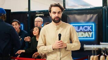 Local reporter transmitting live footage from black friday store opening scene, broadcasting seasonal sales madness and violent desperate crowd of shoppers. News correspondent with mic. Tripod shot. photo