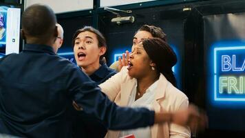 Mad diverse shoppers at store entrance going crazy for Black Friday promotions and deals, pushing through red tape. African american security agent managing crowd control during sales season. photo