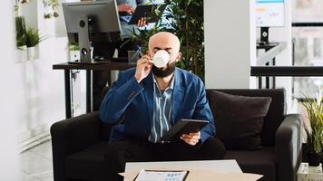 Middle eastern man takes notes on tablet, creating new investment strategy to increase profit. AI developer works on programming analytics, reading statistics in small business office. photo