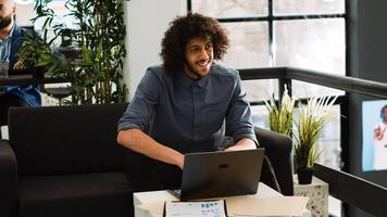 Businessman creating report on laptop in startup open space. Young analyst reviewing company project data before starting development strategy for small business growth, coworking space. photo