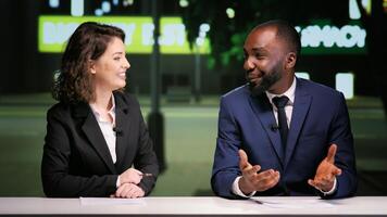 Broadcasters team on night talk show addressing different news topics live in newsroom, hosting entertainment panel on television program. Diverse media reporters presenting midnight segment. photo