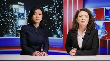 Diverse journalists host night show live on tv network, presenting breaking news segment in newsroom. Media presenters team addressing daily international events with television reportage. photo