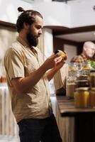 Man in zero waste store taking time to analyze juice, making sure it's made from organic fruits. Customer thoroughly checking food items are safe in environmentally responsible local supermarket photo