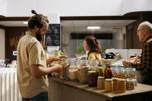 Man in environmentally responsible zero waste store interested in buying food with high nutritional value. Client looking for pantry staples in reusable packaging in local grocery shop photo