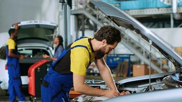 Mechanic in car service uses torque wrench to tighten bolts inside vehicle after fixing components inside. Repair shop employee utilizing professional tools to make sure automobile is properly working photo