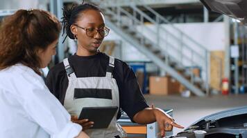Licensed engineer in car service using tablet to calculate repairments invoice for client after fixing damages. Trained expert using device to determine final costs after servicing vehicle, close up photo