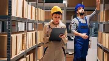 Caucasian woman checking list on papers for inventory, working on stock logistics and counting boxes of merchandise. Female supervisor looking at products placed on depot shelves. Tripod shot. photo