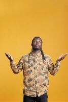 Faithful person asking god for good luck and gratitude, begging for forgiveness. Religious african american man standing with palms faced to sky front of studio camera. Spirituality concept photo