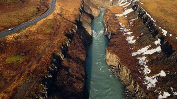 Drone shot of gullfoss river cascade, majestic water stream flowing between colorful snowy hills and fields. Icelandic nature and landscape near waterfall. Slow motion. photo