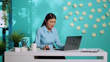 Encantado eufórico oficina trabajador teniendo Estallar de felicidad celebrando empresa éxito. alegre exaltado mujer de negocios aplausos a vistoso escritorio terminado azul estudio antecedentes foto