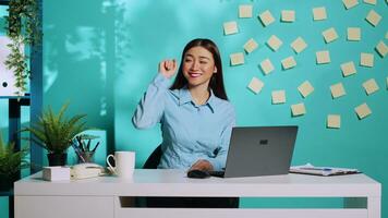 Cheerful chipper upbeat asian woman pointing upward, leftward and rightward using finger and showing positive thumbsigns. Office worker in colourful workplace over blue studio background photo