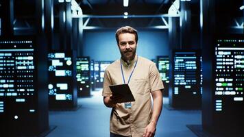 Engineer in high tech facility delivering immense computing power, capable of processing and storing vast amounts of data. Technician walking between server racks rows controlling network resources photo