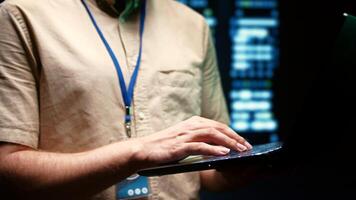 Close up of system administrator using laptop to check operational server clusters. Rackmounts in computer network security data center providing processing and memory resources for several workloads photo