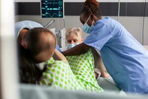 Woman delivery baby in hospital ward, screaming and pushing during caesarean surgery. Medical team and future father comforting pregnant woman with painful contractions in maternity clinic photo