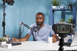 African american vlogger using volume controller console and recording video with professional camera. Blogger creating digital content for social media channel in studio photo