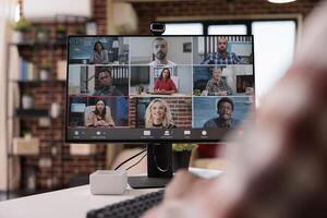 Closeup of computer screen with video call software app showing team of colleagues in conference brainstorming ideas. African american startup employee in internet meeting with people working remote. photo