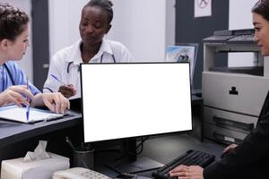 Receptionist manages patient records and schedules appointments typing medical data on computer with white isolated screen. Hospital staff working at health care treatment for patients photo