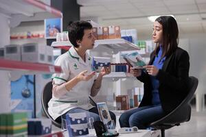 farmacia trabajador explicando Aisan cliente dietético suplementos instrucción, haciendo general médico cheque arriba en farmacia. boticario joven cliente leyendo folleto acerca de mujer salud foto