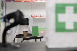 Greenscreen chroma key mock up drugs package standing vertically on chair in drugstore, empty pharmacy filled with pharmaceutical products and vitamins. Health care service support and concept photo