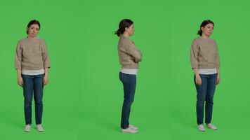 Discontent upset woman acting sad and discouraged posing over greenscreen backdrop, being disappointed and depressed. Young sad adult standing over full body studio background. photo