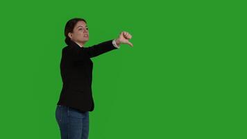 Side view of corporate employee giving thumbs down symbol in studio, doing dislike and negative bad gesture. Businesswoman with office suit expressing disapproval and disagreement on camera. photo