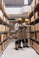Warehouse operators scanning parcel and reading order information on digital tablet. Storehouse coworkers doing goods inventory with bar code scanner and checking stock supply photo