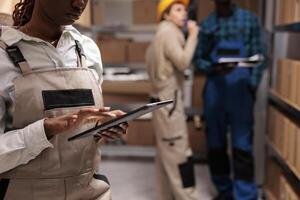 Delivery service warehouse worker monitoring order dispatching process on digital tablet. Shipping business company employee checking parcel information in app before transportation in storehouse photo