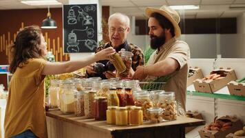 Sustainable zero waste supermarket ran by older storekeeper suggesting products to clients. Local neighborhood grocery store full with customers shopping for organic chemicals free produce photo